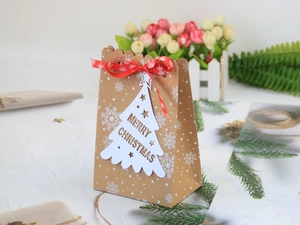 Weihnachtsgeschenktüte aus Kraftpapier mit Schneeflocken, roter Schleife und Anhänger