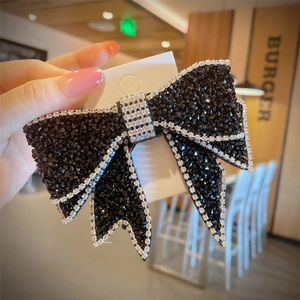 Detail of a large black bow hair clip with sparkling rhinestones and silver crystal edges