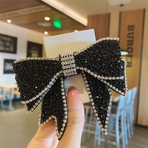 Exaggerated black bow hair clip with dense black beads and silver rhinestone edges