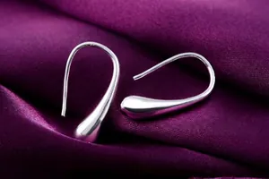Orecchini a goccia in argento lucido su elegante sfondo in seta a pieghe viola