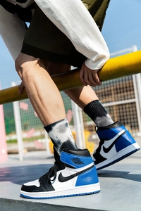 Dynamic view of blue, white, and black high-top sneakers with classic wing logo detail