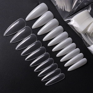 Macro shot of numbered stiletto nail tips in clear and milky white colors on black background
