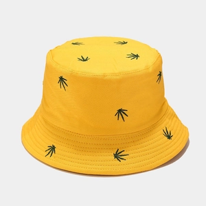 Detail of yellow cotton bucket hat featuring green leaf embroidery and sturdy canvas texture
