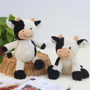 Peluche de vaca manchada en blanco y negro en dos tamaños sobre cesta de mimbre