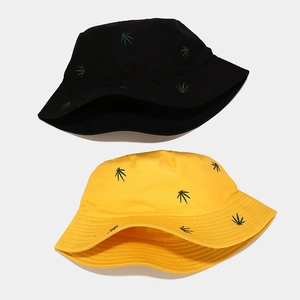 Detail of embroidered green leaf patterns on black and yellow cotton bucket hats