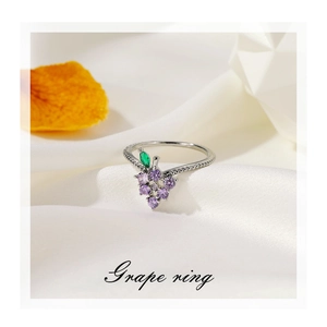 Detailed view of silver grape ring with purple crystals on white satin background
