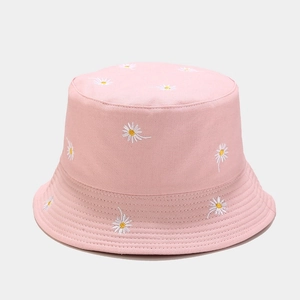Detailed close-up of white daisy embroidery on a soft pink cotton bucket hat fabric