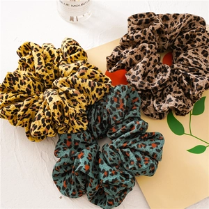 Detailed view of three leopard print oversized scrunchies in yellow, coffee, and blue chiffon
