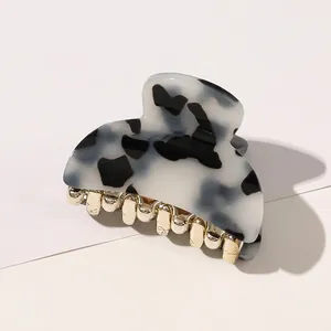 Detail of marble pattern acrylic hair claw clip with golden metal teeth on magazine