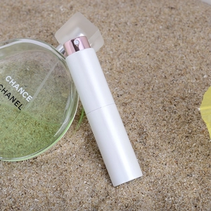Detail of 10ml twist perfume atomizer in white and rose gold on a beach sand background