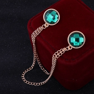 Close-up of golden collar chain featuring faceted green gemstones on red velvet