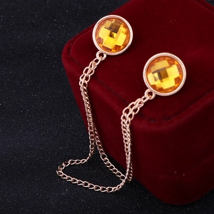 Macro view of a gold-finish collar chain with faceted yellow gemstones on red velvet