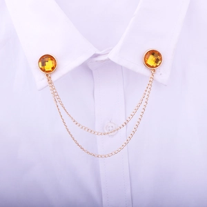 Detail of gold collar pin with yellow gems and tassel chains on white shirt