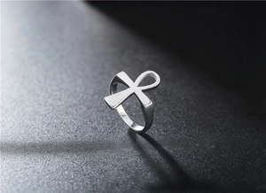Macro shot of polished silver Ankh cross ring detail on a textured dark grey background