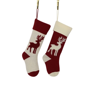 Pair of knitted Christmas stockings with elk pattern in red and white hanging on white background