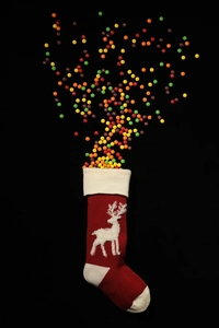 Close-up of red knitted Christmas stocking with reindeer pattern and colorful candies