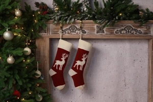 Detail of red knit Christmas stockings with white reindeer hanging on a festive mantel