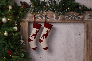 Close-up of knit Christmas stockings with reindeer patterns hanging on a fireplace