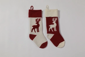 Close-up of knitted Christmas stockings featuring reindeer patterns and hanging loops