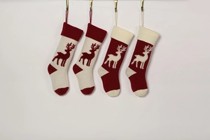Detailed view of four knitted Christmas stockings with reindeer patterns on wall hooks