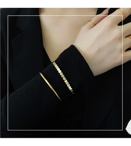Detailed view of gold honeycomb bracelet and sleek minimalist bangles on model's wrist