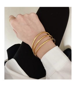 Detail of three stacked minimalist gold-polished stainless steel rings on a female wrist