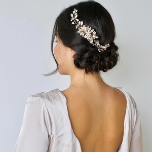 Elegant gold bridal hair comb with pearls and crystals shown on an elegant bun hairstyle