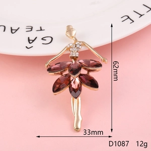 Detail of golden ballet dancer alloy accessory with red crystals and dimensions 62mm by 33mm