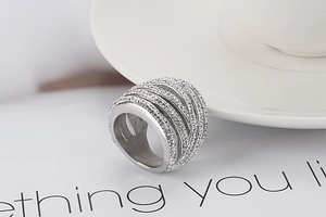 Close-up of a silver multi-layer woven ring with shimmering rhinestones on a white card