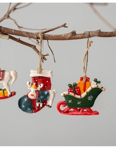 Detail of hand-painted resin reindeer sock and gift sleigh ornaments on a branch