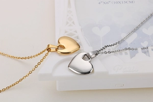Detailed view of heart-shaped pendants in gold and silver finish on white background