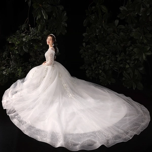 Robe de mariée élégante en dentelle blanche avec manches longues et traîne scintillante