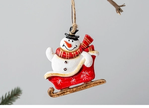 Close-up of resin snowman on red sleigh ornament with jute rope for Christmas tree
