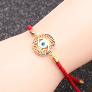 Macro detail of red woven chain bracelet with colorful zircon evil eye charm for women