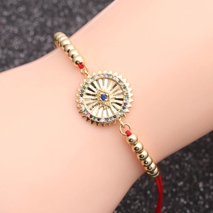 Golden red string chain bracelet with a colorful zircon evil eye pendant on wrist