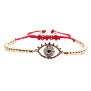 Detailed view of evil eye charm with red zircon pave and adjustable red woven cord