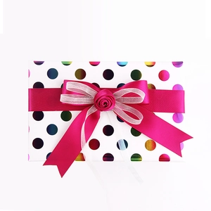 Gift box with colorful polka dots, magenta satin ribbon, and a silk rose decoration