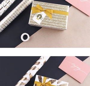 Close-up of gold foil chevron and feather wrapping paper with ribbons and gift tags