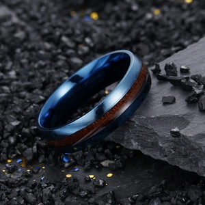 Detailed close-up of 6mm blue stainless steel ring with koa wood grain inlay on rocks