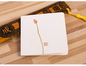 Detailed view of Chinese greeting card with lotus artwork and bamboo scroll on wood surface
