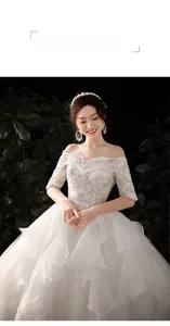 Detail of off-shoulder lace bridal gown with sequin embroidery and layered ruffled skirt