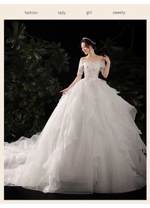 Detail of off-shoulder lace wedding dress with beads and tiered ruffle train