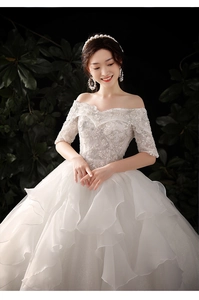 Detail of off-shoulder wedding dress with intricate lace embroidery and sequin beadwork