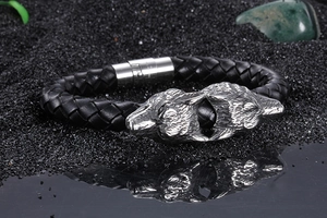 Macro detail of men's braided leather bracelet featuring vintage stainless steel wolf heads