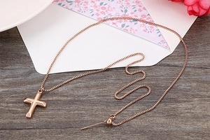 Detail of rose gold cross pendant necklace with adjustable box chain on wooden background