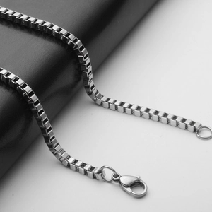 Polished stainless steel box chain necklace with lobster clasp on dark texture
