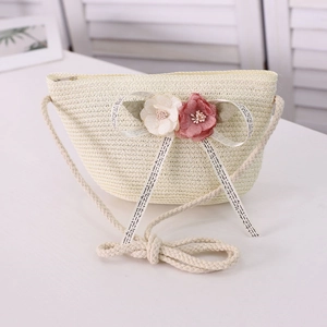 Detail of straw woven crossbody bag featuring floral decor and cotton rope strap