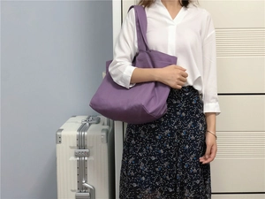 Gedetailleerde textuur van paarse canvas shopper over de schouder in een minimalistische setting