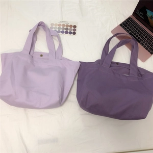 Detail van paarse canvas tote bags met magneetsluiting op een getextureerde achtergrond