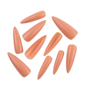Close-up of nude pink stiletto false nails showcasing professional shape and glossy finish